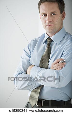 Stock Image - Portrait of businessman standing with arms crossed. Fotosearch