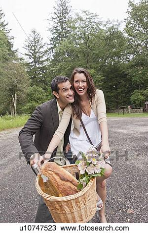 Stock Image - Portrait of couple on bike with basket. Fotosearch