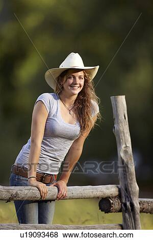 Portrait of cowgirl leaning on fence View Large Photo Image Stock Photo - Portrait of cowgirl leaning on fence. Fotosearch