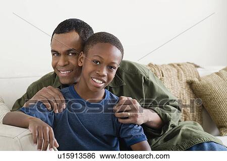 Portrait of Father and Son (12-13) sitting on sofa View Large Photo Image Stock Photograph - Portrait of Father and Son (12-13) sitting on sofa. Fotosearch