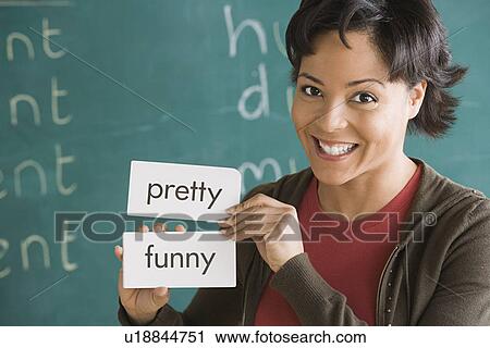 Stock Image - Portrait of female teacher holding text tags. Fotosearch