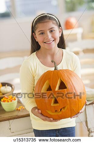Stock Photography - Portrait of girl (10-11) holding Jack o lantern. Fotosearch