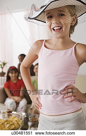 Stock Image - Portrait of girl (10-11) wearing hat with veil at slumber party. Fotosearch