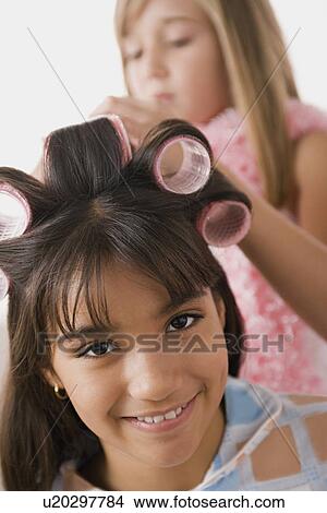 Picture - Portrait of girl (10-11) with curlers and another girl (10-11) in background. Fotosearch