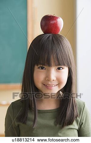 Portrait of girl (6-7) balancing apple on head View Large Photo Image Picture - Portrait of girl (6-7) balancing apple on head. Fotosearch