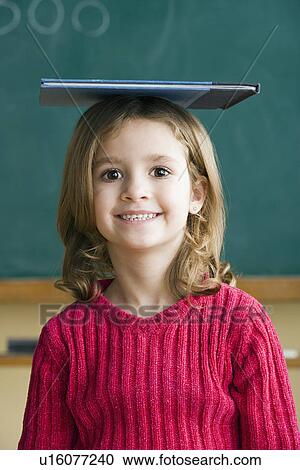 Portrait of girl (6-7) balancing book on head View Large Photo Image Stock Image - Portrait of girl (6-7) balancing book on head. Fotosearch
