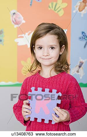 Stock Image - Portrait of girl (6-7) holding letter K. Fotosearch