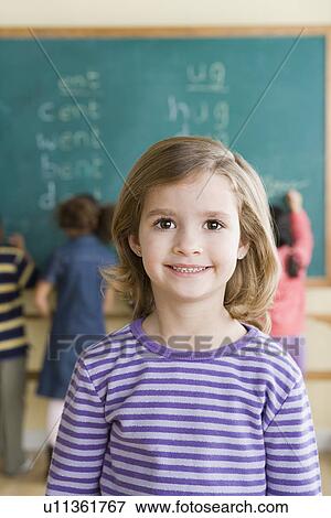 Stock Photo - Portrait of girl (6-7) in classroom. Fotosearch