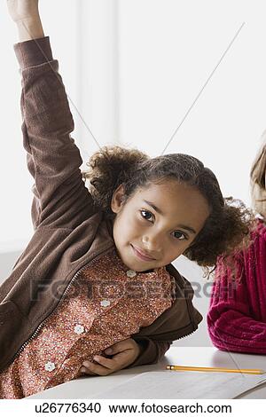 Portrait of girl (6-7) with raised hand in classroom View Large Photo Image Stock Image - Portrait of girl (6-7) with raised hand in classroom. Fotosearch