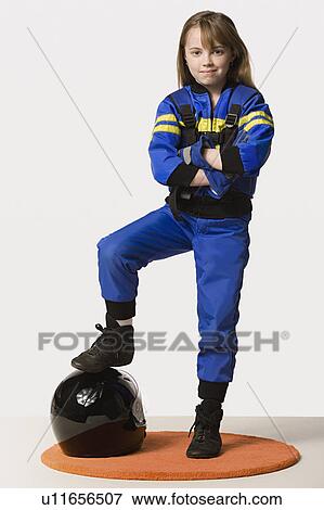 Stock Photo - Portrait of girl (8-9) dressed as racing driver, studio shot. Fotosearch