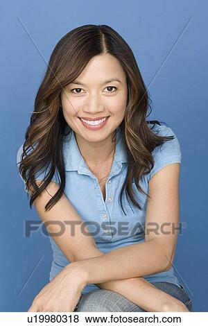 Stock Photo - Portrait of happy asian woman wearing blue polo shirt. Fotosearch