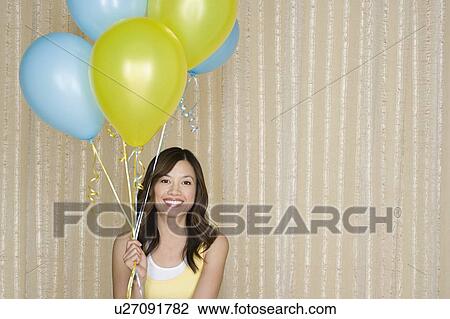 Stock Image - Portrait of happy asian woman with balloons. Fotosearch