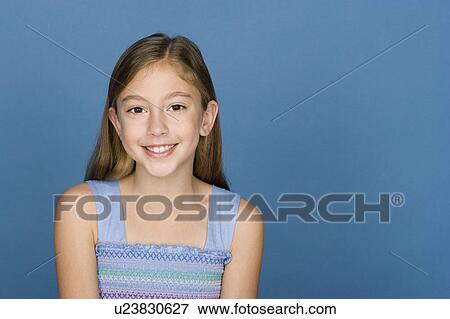 Stock Photo - Portrait of happy girl (8-9) n blue background. Fotosearch