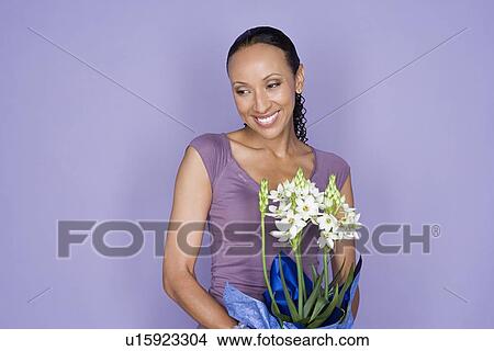 Picture - Portrait of happy mid adult african woman holding flower. Fotosearch