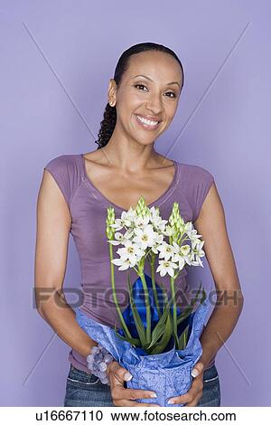 Portrait of happy mid adult african woman holding flower View Large Photo Image Stock Image - Portrait of happy mid adult african woman holding flower. Fotosearch