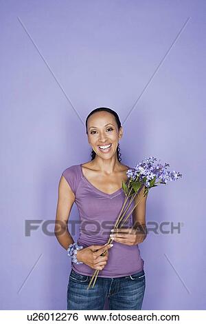 Stock Photograph - Portrait of happy mid adult african woman holding flower. Fotosearch