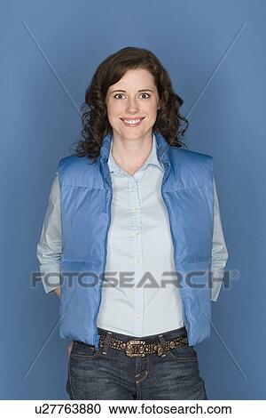 Stock Image - Portrait of happy mid adult woman wearing blue vest. Fotosearch