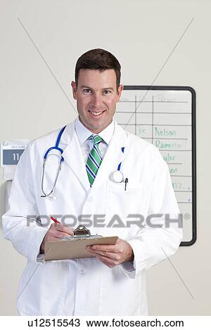 Stock Image - Portrait of male doctor holding clipboard. Fotosearch