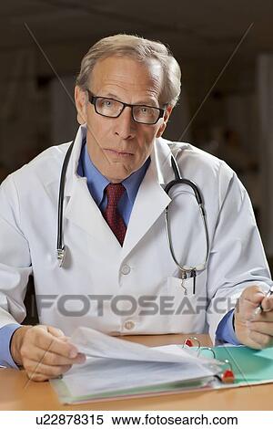 Portrait of male doctor reading files View Large Photo Image Stock Photography - Portrait of male doctor reading files. Fotosearch