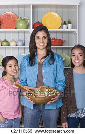 Stock Image - Portrait of mother with two daughters (8-9, 10-11) in kitchen. Fotosearch