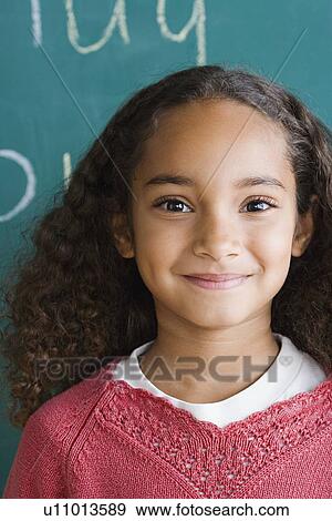 Stock Photo - Portrait of schoolgirl (6-7) against blackboard. Fotosearch