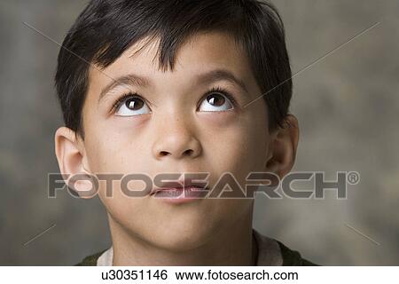 Stock Photograph - Portrait of smiling boy (8-9) looking up, studio shot. Fotosearch