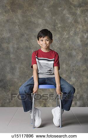 Portrait of smiling boy (8-9) sitting on stool, studio shot View Large Photo Image Stock Photograph - Portrait of smiling boy (8-9) sitting on stool, studio shot. Fotosearch