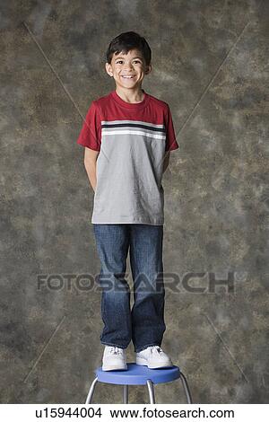 Portrait of smiling boy (8-9) standing on stool, studio shot View Large Photo Image Picture - Portrait of smiling boy (8-9) standing on stool, studio shot. Fotosearch