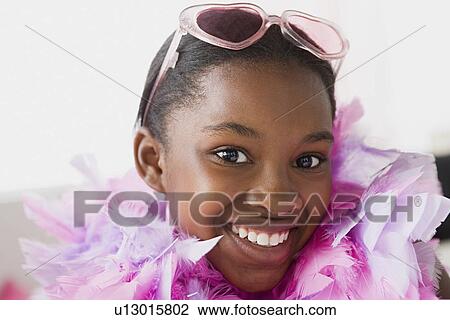 Stock Image - Portrait of smiling girl (10-11) wearing feather boa and sunglasses. Fotosearch
