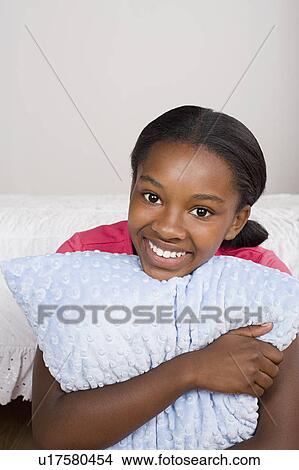 Picture - Portrait of smiling girl (10-11) with pillow. Fotosearch