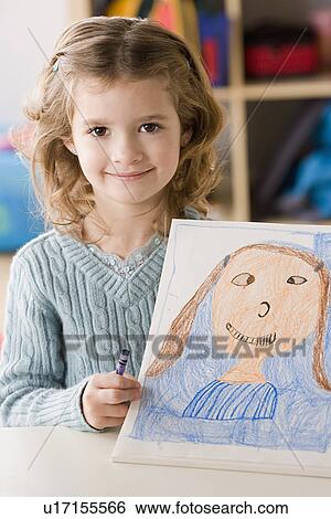 Stock Photograph - Portrait of smiling girl (6-7) showing her drawing. Fotosearch
