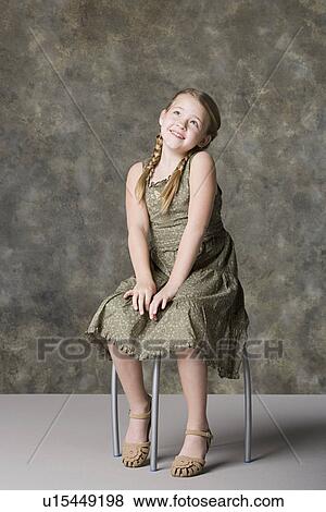 Portrait of smiling girl (8-9) sitting on stool View Large Photo Image Stock Photo - Portrait of smiling girl (8-9) sitting on stool. Fotosearch