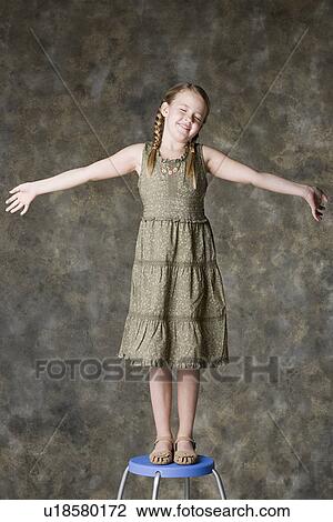 Portrait of smiling girl (8-9) standing on stool, studio shot View Large Photo Image Stock Image - Portrait of smiling girl (8-9) standing on stool, studio shot. Fotosearch