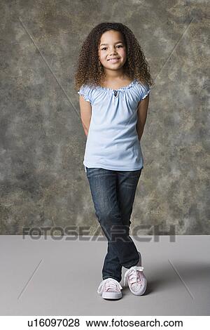 Stock Photo - Portrait of smiling girl (8-9) standing, studio shot. Fotosearch