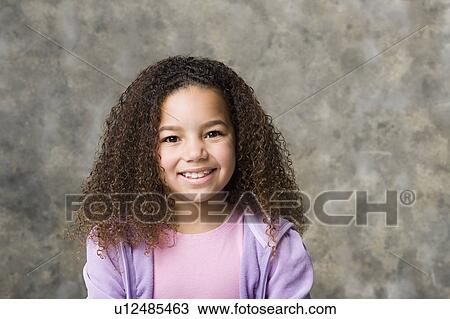 Stock Image - Portrait of smiling girl (8-9), studio shot. Fotosearch