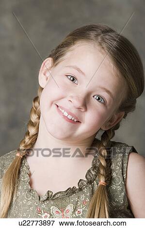 Stock Photo - Portrait of smiling girl (8-9) with braids, studio shot. Fotosearch