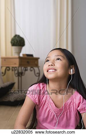 Stock Photography - Portrait of smiling girl (8-9) with headphones. Fotosearch