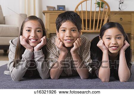 Stock Photograph - Portrait of smiling siblings (8-9, 10-11) lying on floor. Fotosearch