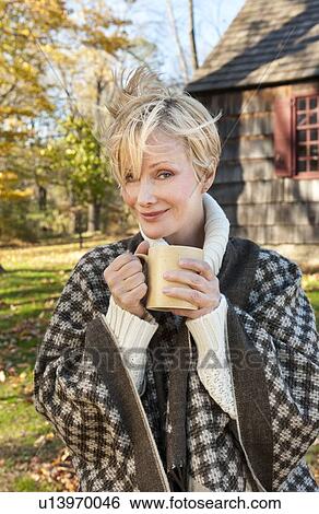 Portrait of smiling woman holding mug in front of cottage house in Autumn View Large Photo Image Stock Photograph - Portrait of smiling woman holding mug in front of cottage house in Autumn. Fotosearch