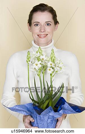 Portrait of smiling woman holding flowers, studio shot View Large Photo Image Picture - Portrait of smiling woman holding flowers, studio shot. Fotosearch