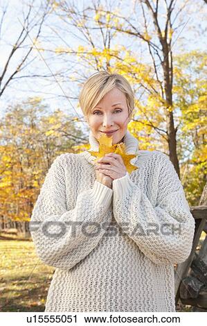 Portrait of smiling woman holding leaves in Autumn forest View Large Photo Image Stock Image - Portrait of smiling woman holding leaves in Autumn forest. Fotosearch