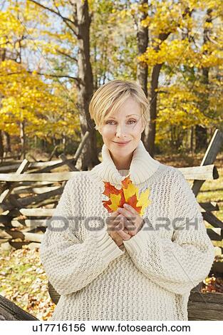 Portrait of smiling woman holding leaves in Autumn forest View Large Photo Image Stock Photograph - Portrait of smiling woman holding leaves in Autumn forest. Fotosearch