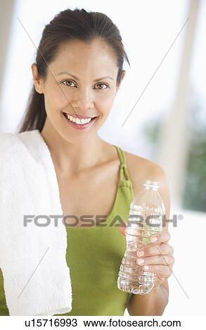 Stock Image - Portrait of smiling woman holding water after training. Fotosearch