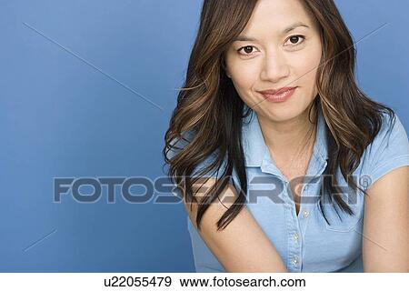 Stock Photo - Portrait of smiling woman on blue background, studio shot. Fotosearch