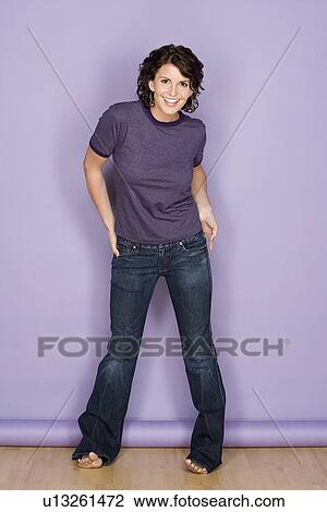 Stock Image - Portrait of smiling woman on purple background, studio shot. Fotosearch