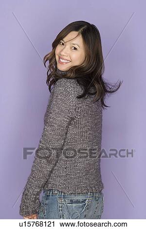 Stock Image - Portrait of smiling woman on purple background, studio shot. Fotosearch