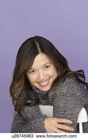 Stock Image - Portrait of smiling woman on purple background, studio shot. Fotosearch