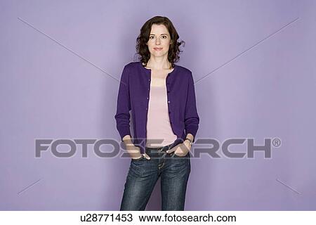 Stock Image - Portrait of smiling woman on purple background, studio shot. Fotosearch
