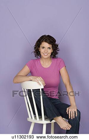 Portrait of smiling woman sitting on chair with purple background, studio shot View Large Photo Image Stock Image - Portrait of smiling woman sitting on chair with purple background, studio shot. Fotosearch