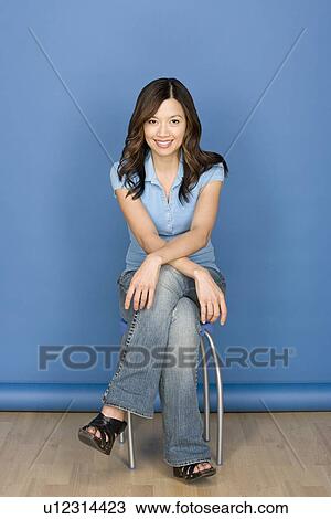 Portrait of smiling woman sitting on chair with blue background, studio shot View Large Photo Image Stock Image - Portrait of smiling woman sitting on chair with blue background, studio shot. Fotosearch
